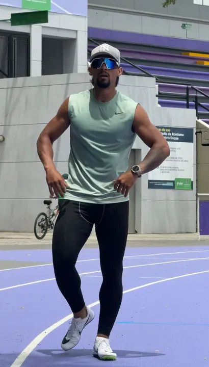 Eros hoy: de pie en la pista atlética, con ropa deportiva, a color